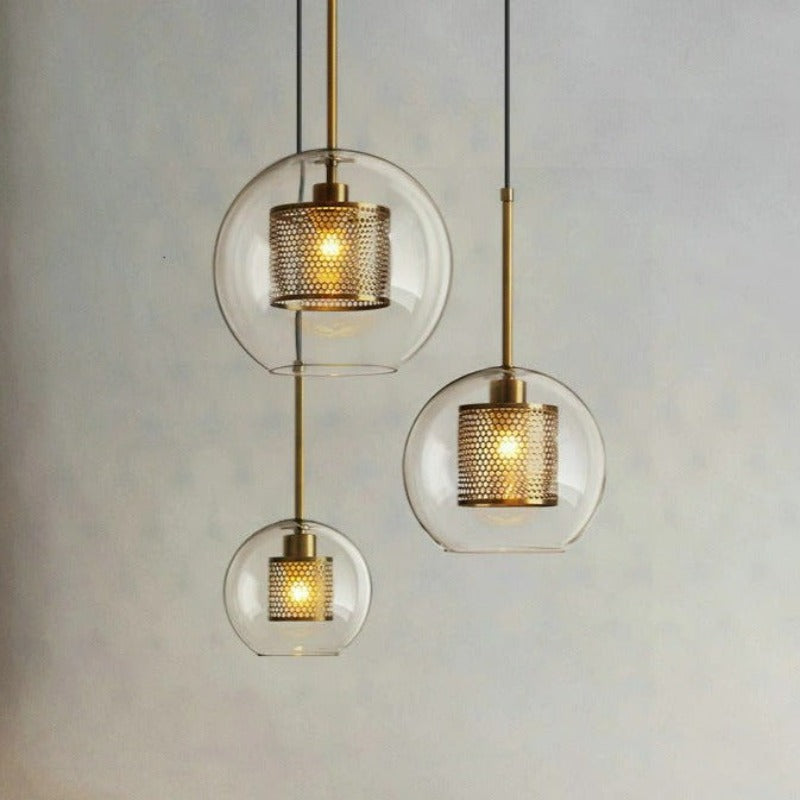 clear glass pendant lights with interior honeycomb shade shown in three sizes in brushed gold finish