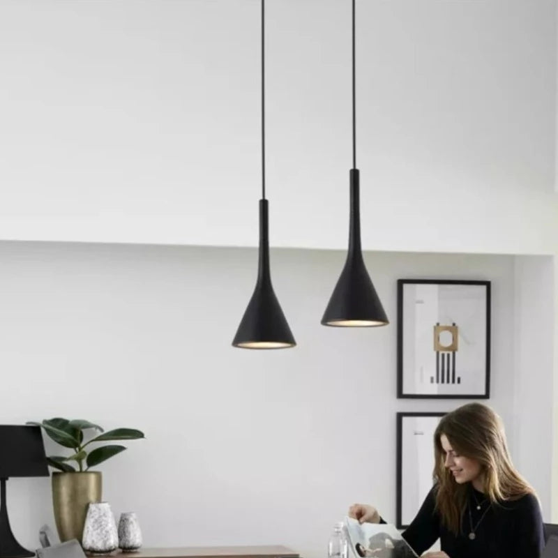 Modern Scandinavian style pendant light shown in black hanging over a dining table