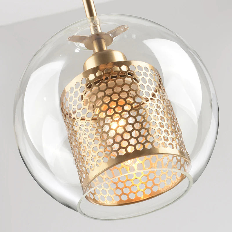 close up view of clear glass pendant lights with interior honeycomb shade shown in brushed gold finish