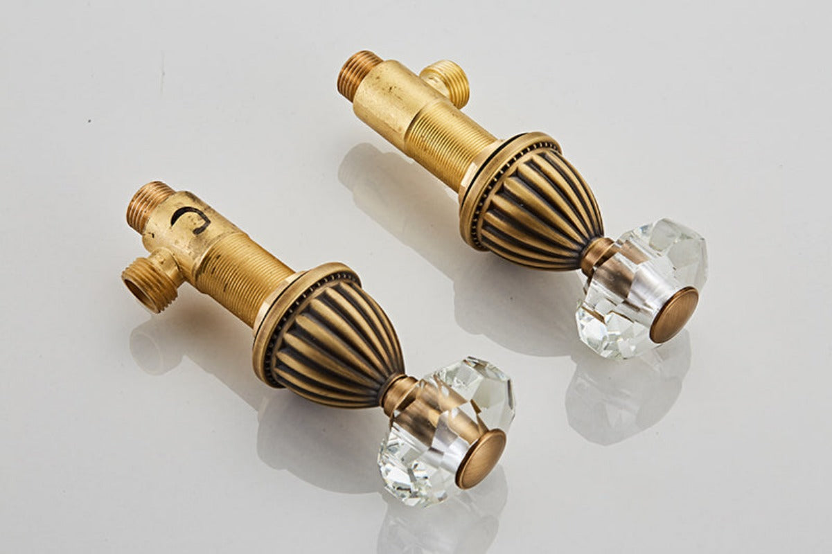 Close up view of faceted crystal bathroom faucet handles shown in antique gold finish
