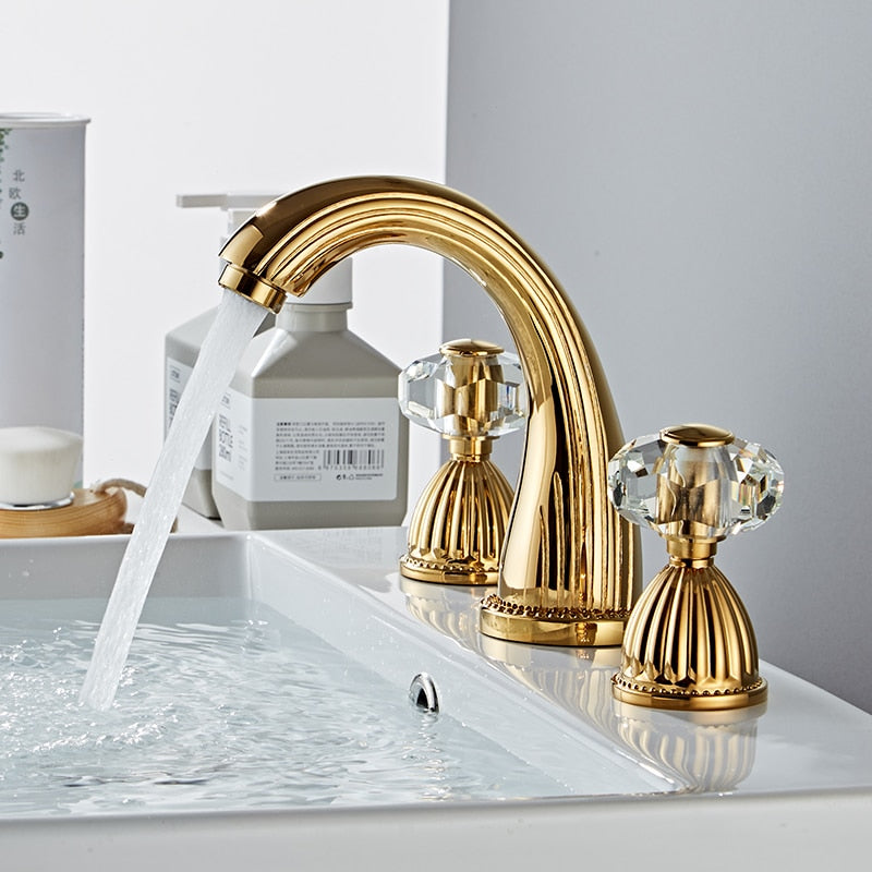 Elegant gold three hole bathroom faucet with faceted crystal handles. Fluted Design. Deck mounted, three hole with two handles
