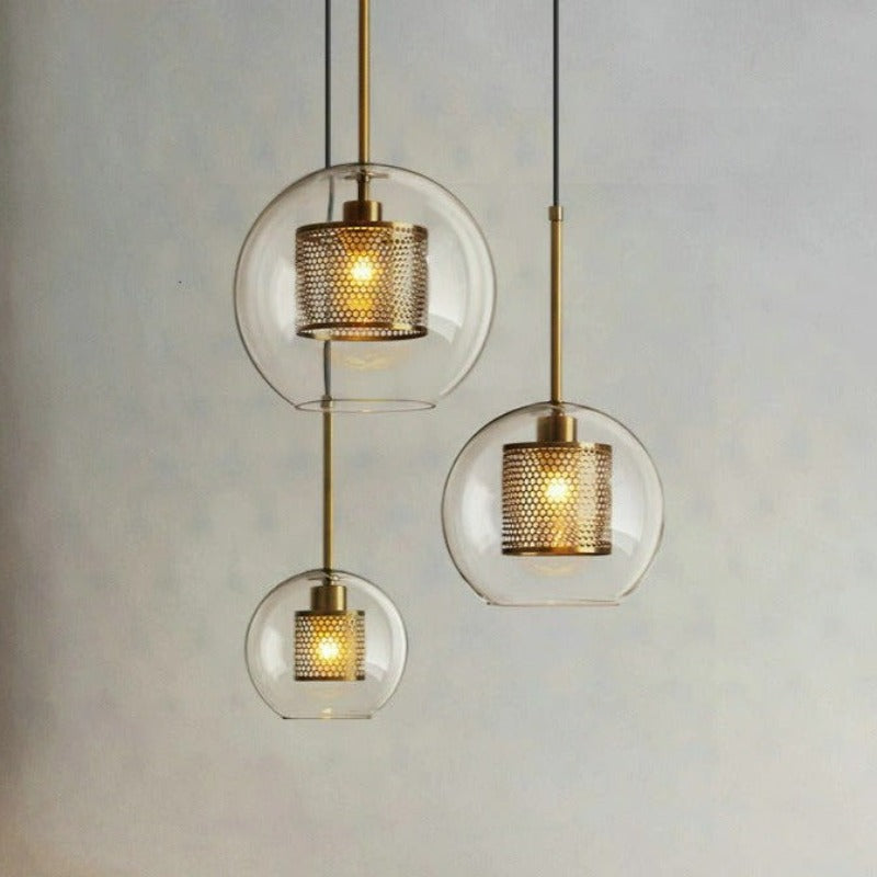 clear glass pendant lights with interior honeycomb shade shown  in three sizes in brushed gold finish