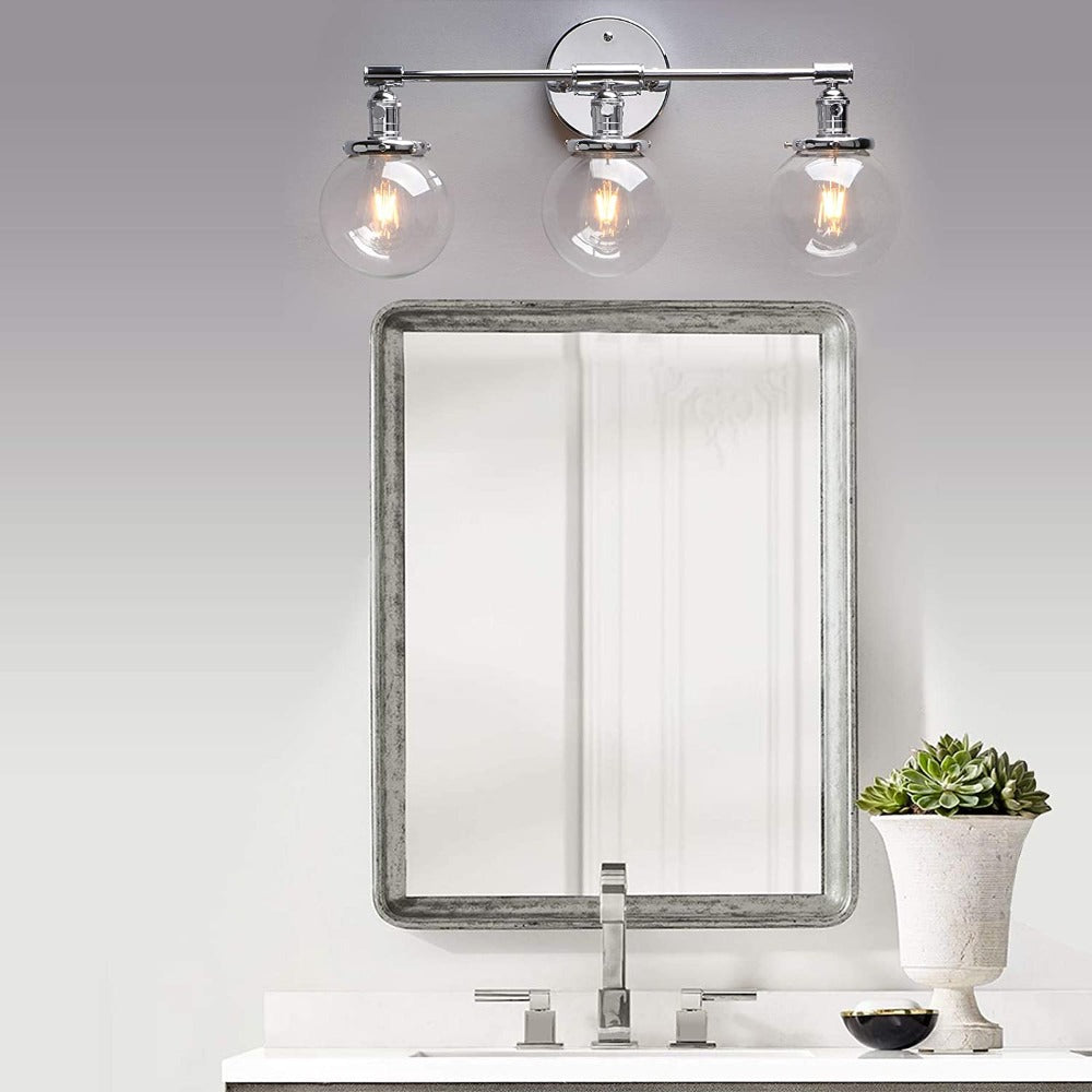 Three Light Bathroom Vanity Lighting with Clear Glass Globes with polished chrome hardware shown over a bathroom vanity