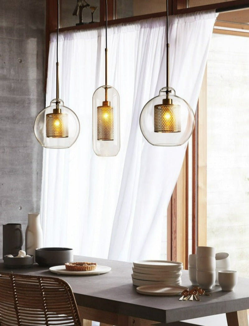 clear glass pendant lights with interior honeycomb shade shown in brushed gold finish shown over a dining room table