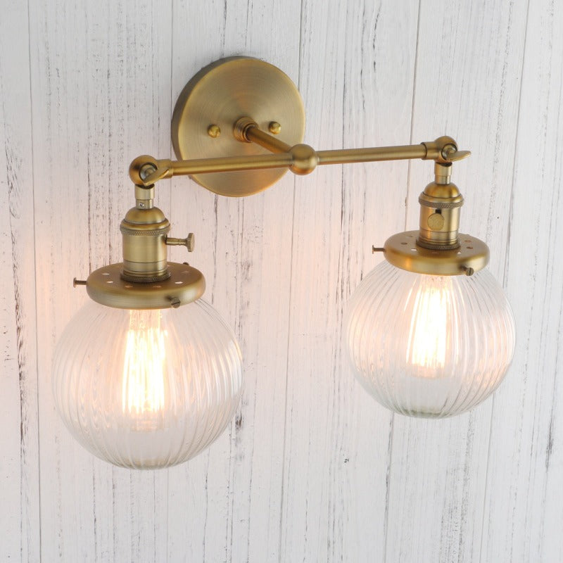 Vintage Double Wall Sconce with clear ribbed glass globes shown in brushed gold shown with light on