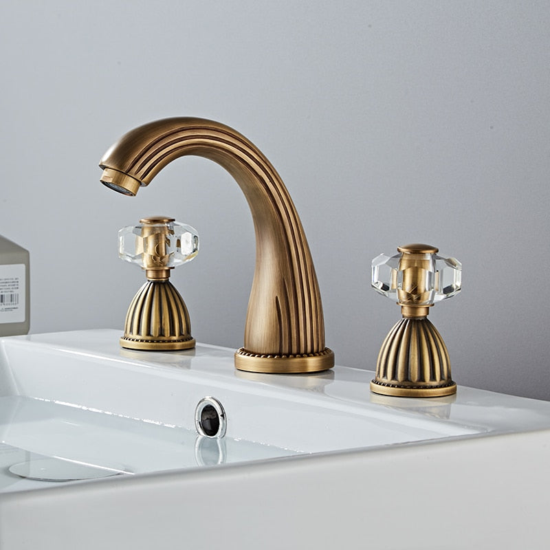 Elegant antique bronze three hole bathroom faucet with faceted crystal handles. Fluted Design. Deck mounted, three hole with two handles