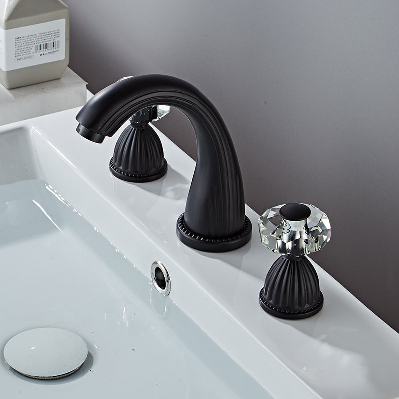 Side view of Matte black bathroom faucet  with faceted crystal handles. Fluted Design. Deck mounted, three hole with two handles
