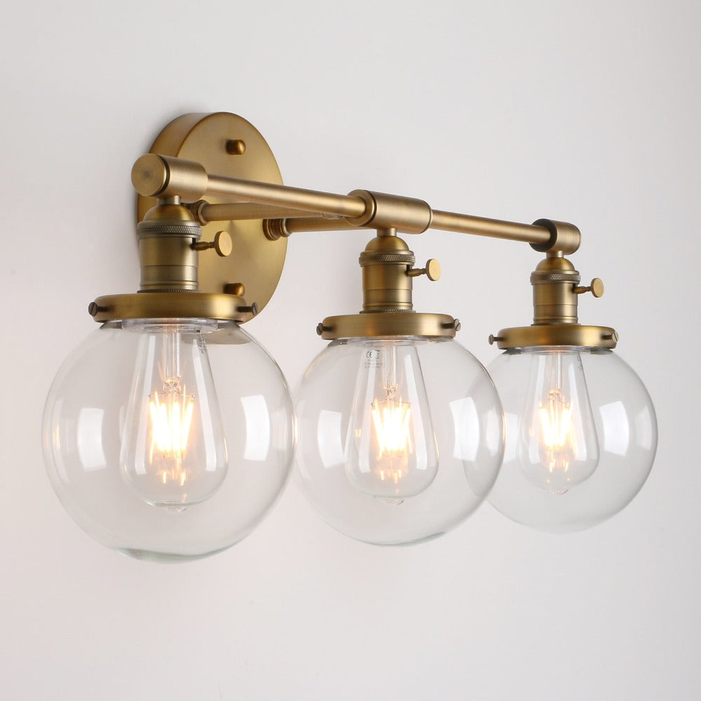 Three Light Bathroom Vanity Lighting with Clear Glass Globes shown in brushed antique gold