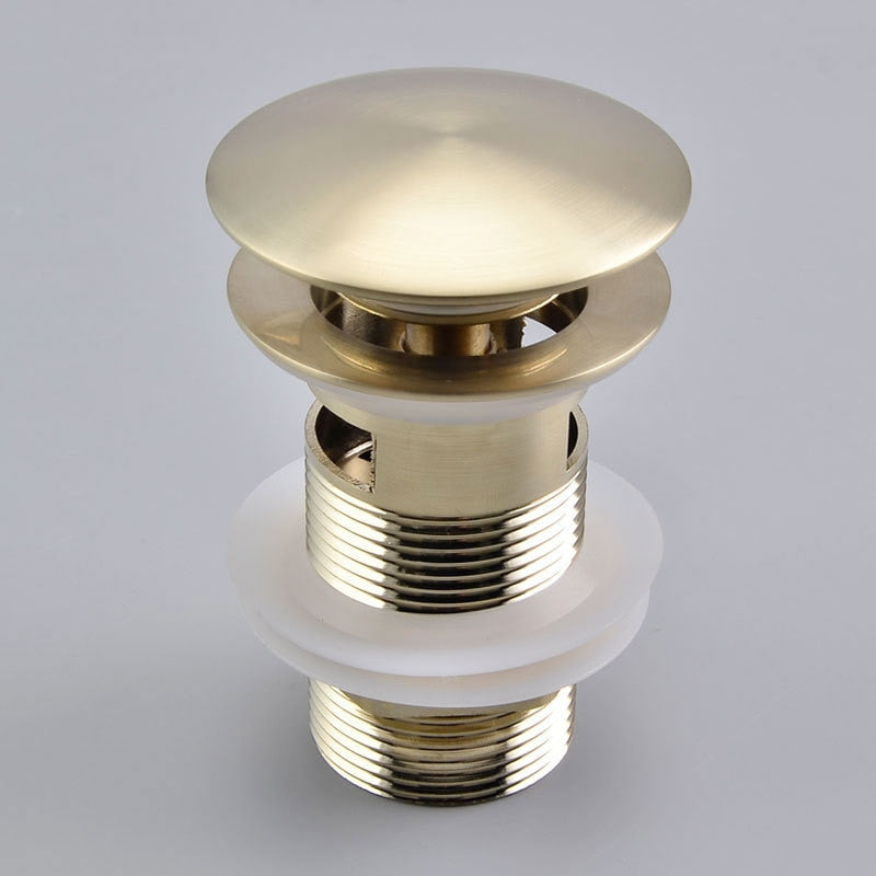 close up image of pop up/push down bathroom sink drain in brushed gold