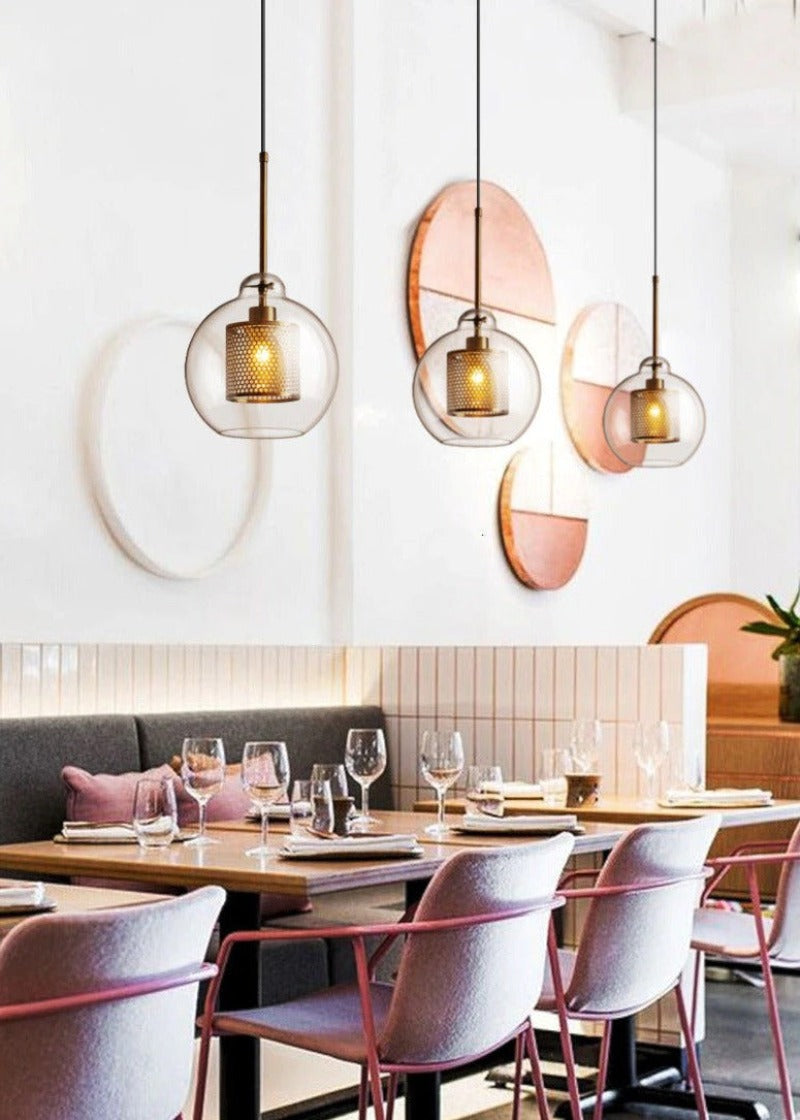 clear glass pendant lights with interior honeycomb shade shown in brushed gold finish hanging in a restaurant setting