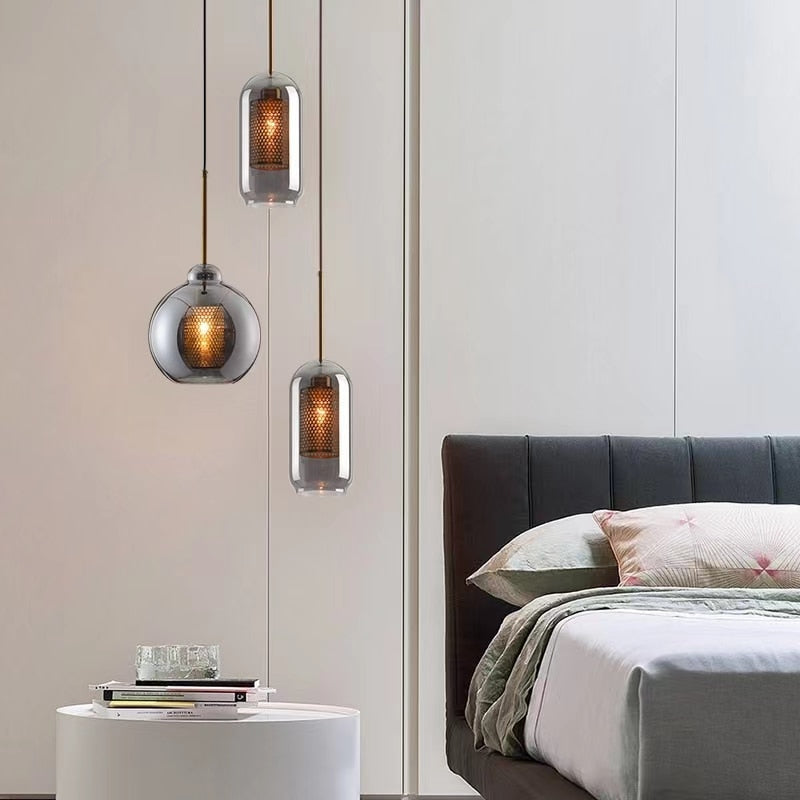 smoky grey glass pendants with honeycomb interior shade that casts a soft pattern of light shown in three different shapes shown in bedroom setting