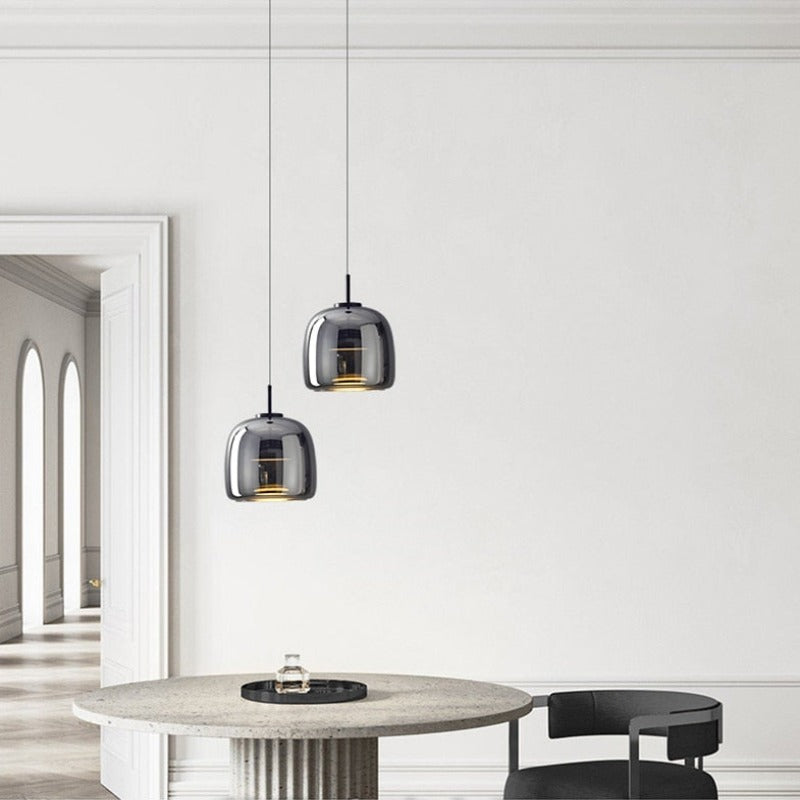 Modern pendant lighting with reflective smoky grey shade shown hung over a modern dining table
