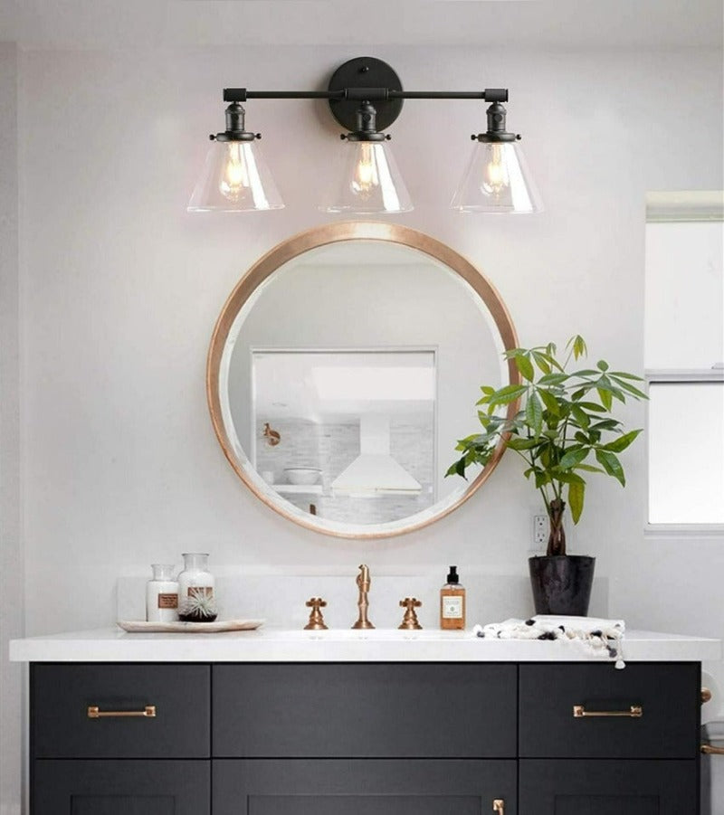 Vintage three light Vanity Wall Sconce in matte black shown above bathroom vanity sink