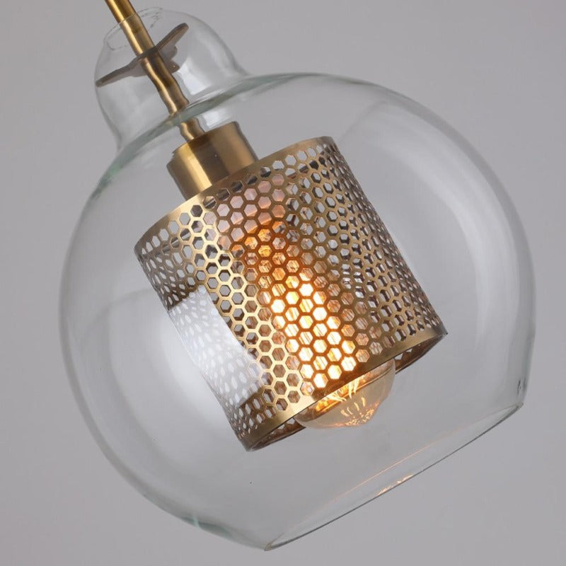 close up of classic shape clear glass pendant lights with interior honeycomb shade shown in brushed gold finish