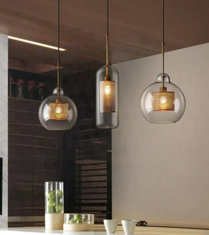 three clear glass pendant lights with interior honeycomb shade shown in brushed gold finish over a kitchen island